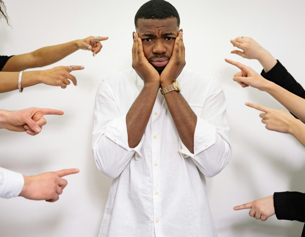 A man looking distressed with many fingers pointed accusingly at him.